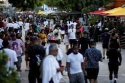 FILE - People walk along Ocean Drive during spring break festivities, amid the coronavirus outbreak, in Miami Beach, Florida, March 5, 2021.