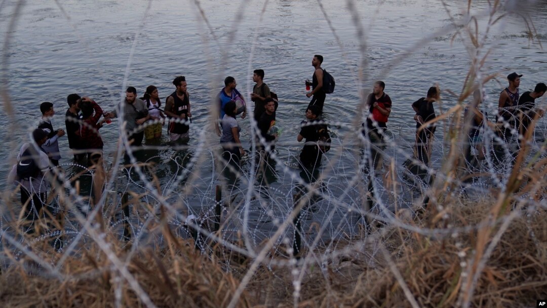 FILE - Migrants wait to climb over concertina wire after they crossed the Rio Grande and entered the U.S. from Mexico, Sept. 23, 2023, in Eagle Pass, Texas. An appeals court Tuesday issued an order putting a controversial Texas border law back on hold. 