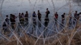 FILE - Migrants wait to climb over concertina wire after they crossed the Rio Grande and entered the US from Mexico, Sept. 23, 2023, in Eagle Pass, Texas.