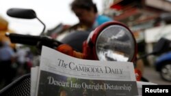 FILE - A woman buys the final issue of The Cambodia Daily newspaper at a store along a street in Phnom Penh, Cambodia, Sept. 4, 2017. 