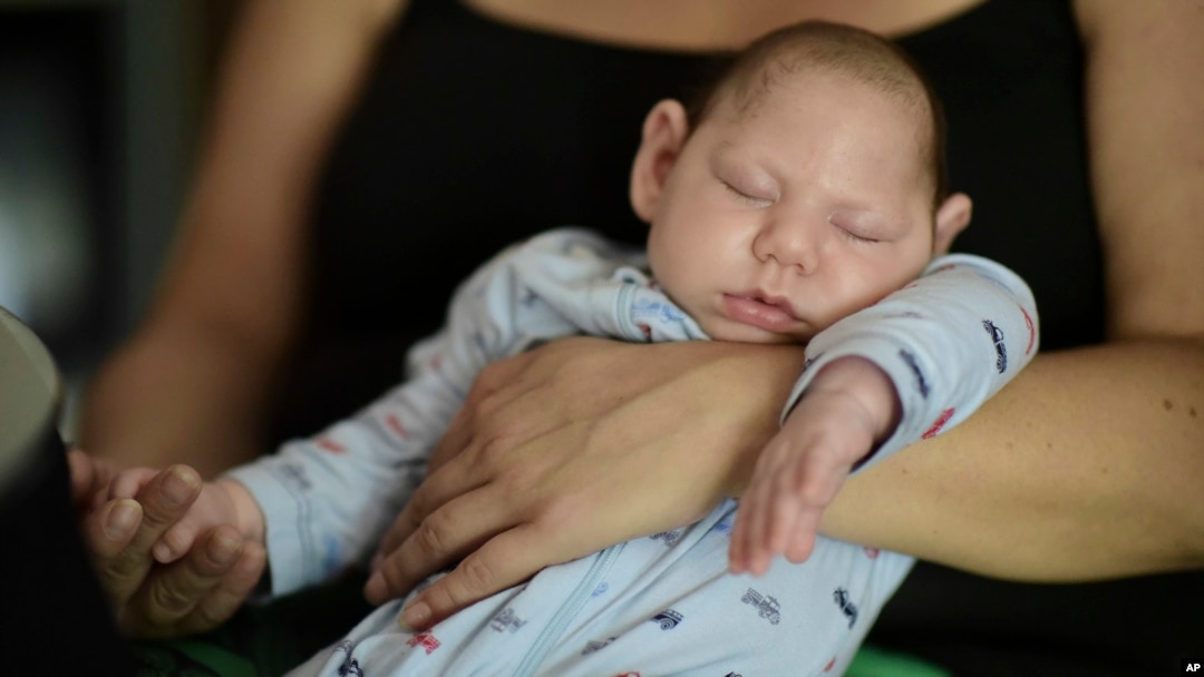 FILE - Two-month-old Inti Perez, diagnosed with microcephaly linked to the mosquito-borne Zika virus, is cradled by his mother, in Bayamon, Puerto Rico. The U.S. Centers for Disease Control and Prevention has projected a surge of cases in 2017 year.