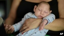 FILE - Two-month-old Inti Perez, diagnosed with microcephaly linked to the mosquito-borne Zika virus, is cradled by his mother, in Bayamon, Puerto Rico. The U.S. Centers for Disease Control and Prevention has projected a surge of cases in 2017 year.