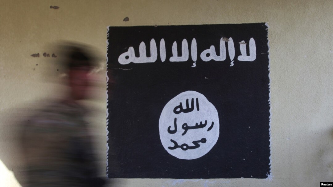 Seorang tentara berjalan melewati bendera hitam yang biasa digunakan oleh militan ISIS.
