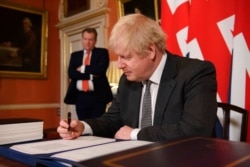 UK chief trade negotiator David Frost looks on as Britain's Prime Minister Boris Johnson signs the EU-UK Trade and Cooperation Agreement at 10 Downing Street, London, Dec. 30, 2020.