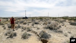 A visitor takes a photo of a crack on the ground following recent earthquakes Sunday, July 7, 2019, outside of Ridgecrest, Calif. (AP Photo/Marcio Jose Sanchez)