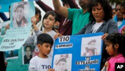 Relatives of Luis Carlos Nolasco, one of the sailors from the missing ARA San Juan submarine, gather outside the navy base in Mar del Plata, Argentina, Dec. 3, 2017, with a sign that reads in Spanish "Uncle, we wait for you, we miss you, we love you."