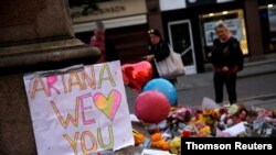 ARCHIVO - Personas observan tributos y flores para las víctimas del concierto de Ariana Grande en Manchester, Gran Bretaña, el 23 de mayo de 2017.