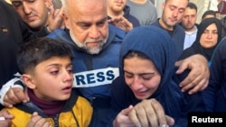 Palestinian journalist Wael Al-Dahdouh embraces family members as they attend the funeral of his son, journalist Hamza Al-Dahdouh, after he was killed in an Israeli strike, in Rafah in the southern Gaza Strip, Jan. 7, 2024.