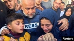Al Jazeera journalist Wael Al-Dahdouh hugs his daughter and son as they attend the funeral of his son, Palestinian journalist Hamza Al-Dahdouh, after Hamza was killed in an Israeli strike, in Rafah in the southern Gaza Strip, Jan. 7, 2024. 