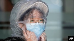 A Chinese woman uses a plastic bag to cover her head while waiting for her flight at the departure area of Manila's International Airport, Philippines on Wednesday, March 18, 2020. 