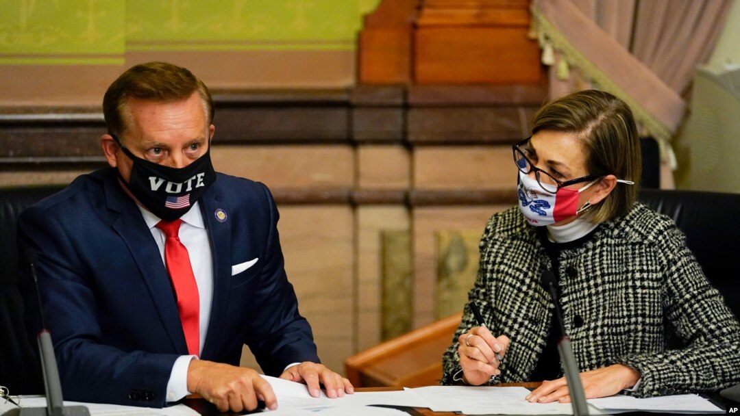 Buramatari wa reta ya Iowa, Kim Reynolds iburyo, n'umunyamabanga mukuru w'iyo reta Paul Pate, ibubamfu baharura amajwi y'intumwa zihagarariye abatoye, kw'italiki 14/12/2020 i Des Moines, Iowa.