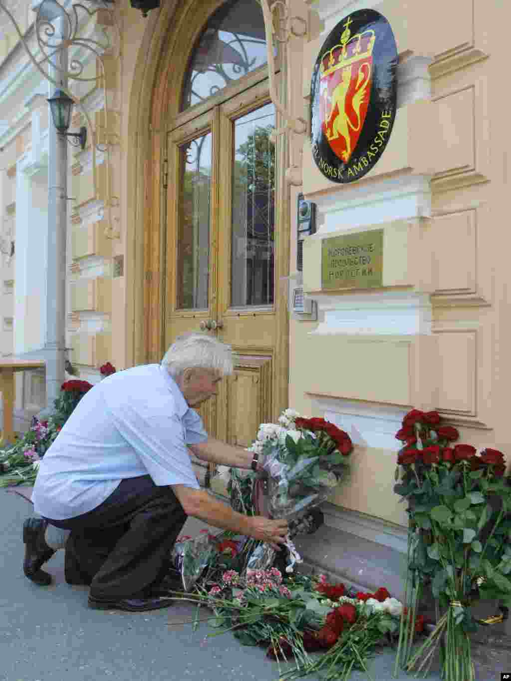 A man puts a flower tribute at the entrance in front of the Embassy of Norway in Moscow, Russia, in memory of the explosion's and shooting's victims. (AP)