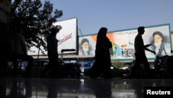 People walk past a mural depicting the late leader of the Islamic Revolution Ayatollah Ruhollah Khomeini and Iran's Supreme Leader Ayatollah Ali Khamenei on a building in a street in Tehran, Iran, Oct. 7, 2024. (Majid Asgaripour/WANA via Reuters)