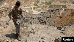 Un membre de l'armée libanaise détient les restes de munitions israéliennes alors qu'il se tient près des dégâts causés par les frappes aériennes israéliennes à Marjayoun, près de la frontière avec Israël, Liban, le 5 août 2021.
