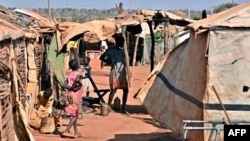 FILE - An internally displaced Somali girl carries her sibling as they wait to collect food relief from the World Food Program (WFP) at a settlement in the capital, Mogadishu, in 2011.