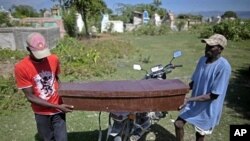Two men carry the coffin of Frist Fleurant, 10, who died of cholera, before his burial in Rossignol, Haiti, 24 Oct. 2010.