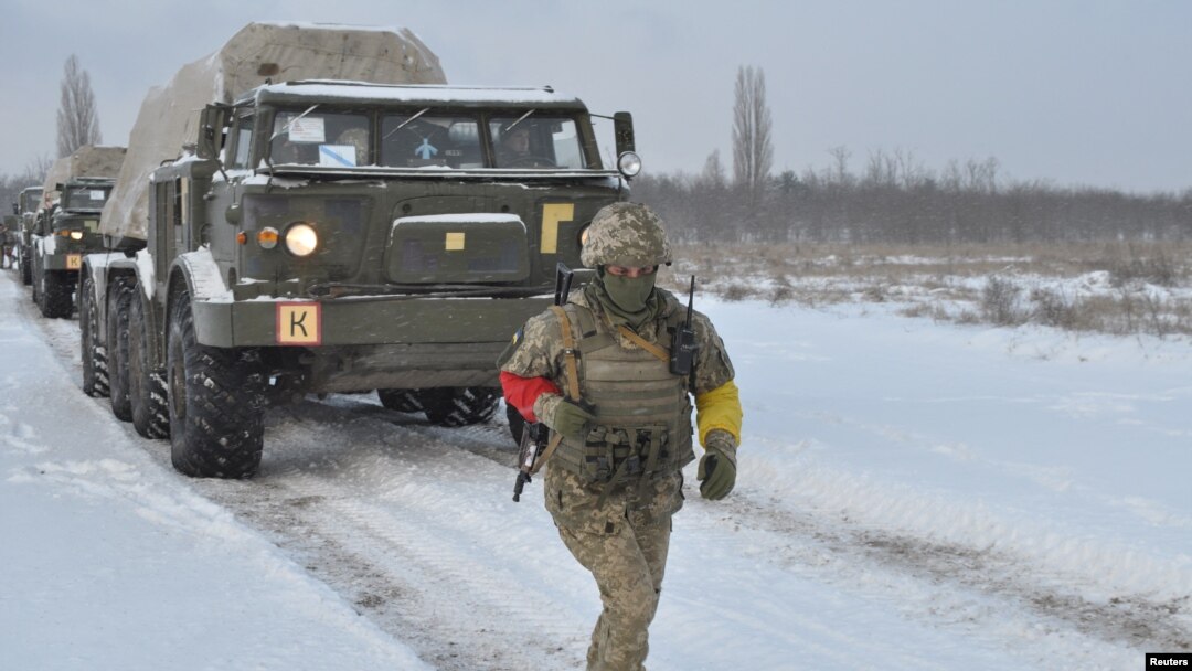 A service member of the Ukrainian Armed Forces runs near self-propelled multiple rocket launcher systems during drills in the Kherson region, Ukraine, in this handout picture released Feb. 1, 2022. 