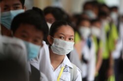 FILE - Students line up to sanitize their hands to avoid the contact of coronavirus before their morning class at a high school in Phnom Penh, Cambodia, Jan. 28, 2020.