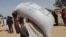 A worker of World Food Programme (WFP) carries a bag of relief grains to be distributed to Sudanese refugees who have fled the violence in their country, near the border between Sudan and Chad, in Koufroun, Chad April 28, 2023.