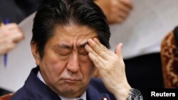 Japan's Prime Minister Shinzo Abe touches his face during an upper house committee session at the parliament...