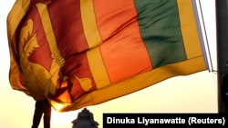 Seorang perwira Angkatan Udara memegang bendera nasional Sri Lanka saat matahari terbenam di Galle Face Green di Kolombo, 2 Februari 2013. (Foto: REUTERS/Dinuka Liyanawatte)