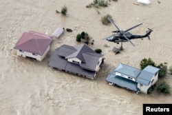 An aerial view shows a Japan Self-Defense Force helicopter flying over residential areas flooded by the Chikuma River following Typhoon Hagibis in Nagano, Japan, Oct. 13, 2019, in this photo taken by Kyodo.