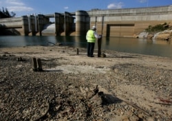 FILE - Dick Pearson from the Sydney Catchment Authority stands in front of Sydney's Warragamba Dam to show the lowest level the dam has ever been.