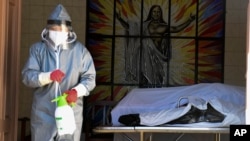 A health worker disinfects the area next to a coffin with the remains of a recently deceased resident of the San Jose nursing home in Cochabamba, Bolivia, July 16, 2020.