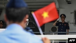 FILE - Vietnamese personnel salute flag-waving Philippine Coast Guard personnel as their Vietnam Coast Guard ship makes a port call during a goodwill visit at a port in Manila on Aug. 5, 2024.