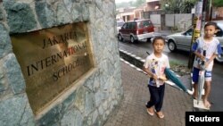 Dua orang anak ojek payung di depan kampus Jakarta International School.