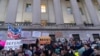 People listen to speakers during a rally against Elon Musk outside the Treasury Department in Washington, Feb. 4, 2025. 