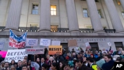 People listen to speakers during a rally against Elon Musk outside the Treasury Department in Washington, Feb. 4, 2025. 