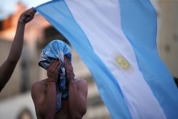 Fans of Argentine soccer great Diego Maradona wave an Argentina flag as they gather to mourn his death, at the Obelisk of Buenos Aires, Argentina, Nov. 25, 2020.