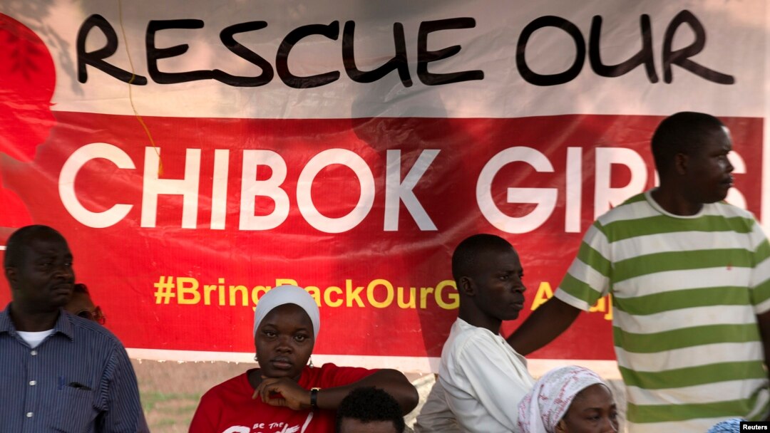 Protesters from the remote town of Chibok stand next to a poster reading "Rescue our Chibok girls," at a protest calling for the release of abducted schoolgirls, in Abuja, Nigeria, May 16, 2014.