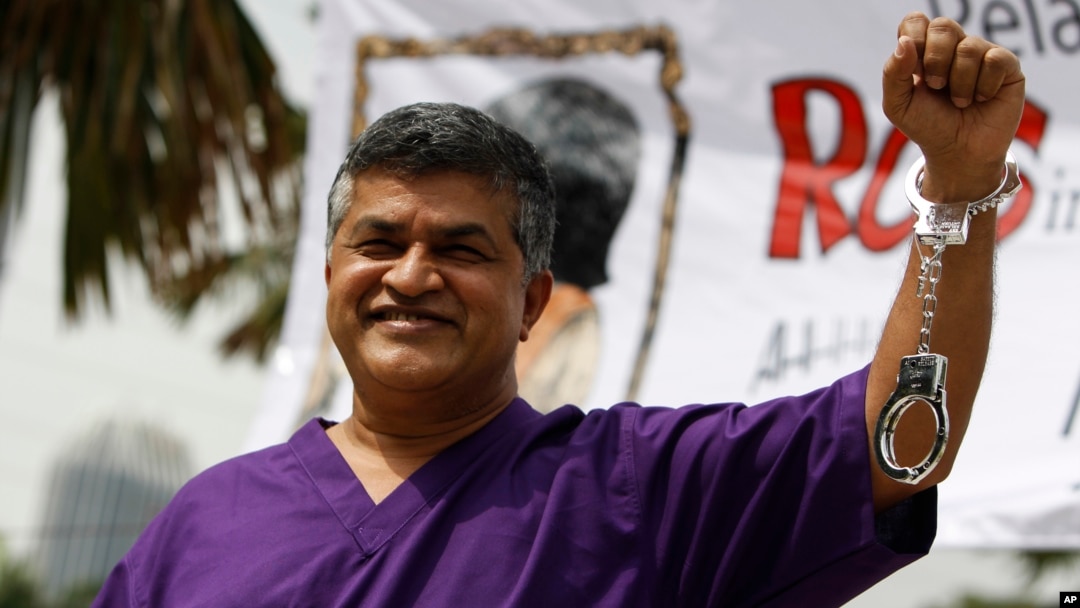 Kartunis Malaysia Zulkifli Anwar Alhaque, yang dikenal dengan nama Zunar, mengenakan seragam tahanan dan borgol plastik berpose bagi para fotografer dalam peluncuran bukunya di Petaling Jaya, Malaysia (14/2).