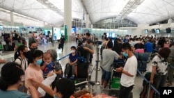 People queue up to check in as some of them are moving to the U.K. at the Hong Kong airport, June 30, 2021. 