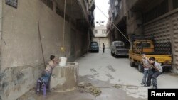 FILE - Boys use a bucket to extract water from a well in Arbeen, in the eastern Damascus suburb of Ghouta. Facing water shortages, residents started drilling wells to extract water to be used for drinking and domestic use, May 6, 2014. 