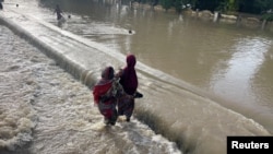 FILE - Residents walk as they leave the flooded areas in Maiduguri, Nigeria, Sept. 15, 2024. Nigeria is grappling with severe floods in northeastern Borno state where a dam burst its walls after heavy rains. 