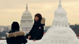 中国游客与美国国会大厦雪雕合影，背景是真实的国会大厦，上面装饰着美国当选总统唐纳德·特朗普即将就职的旗帜。(2025年1月13日)