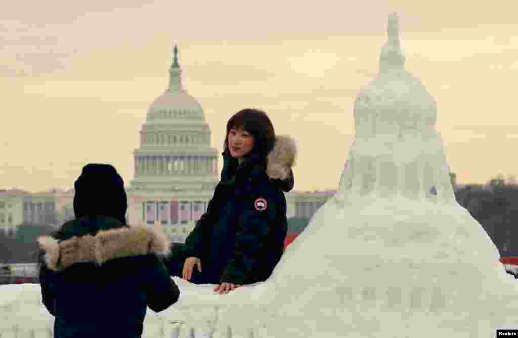 Tourists from China pose for photos with a snow sculpture of the U.S. Capitol with the actual Capitol in the background, in Washington.