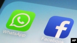 FILE - This Feb. 19, 2014, file photo, shows WhatsApp and Facebook app icons on a smartphone in New York. Global messaging service WhatsApp says it will start sharing the phone numbers of its users with Facebook, its parent company.