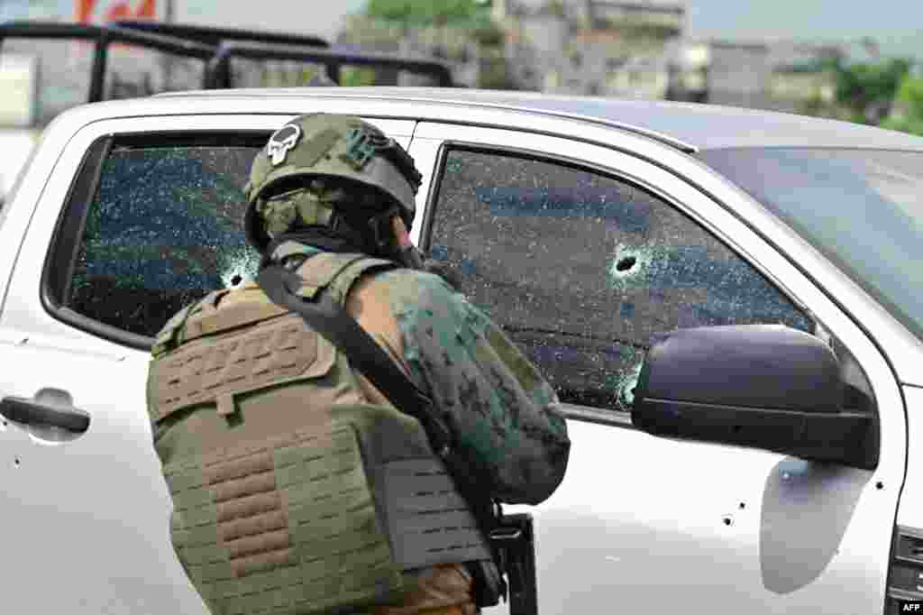 A military officer observes bullet impacts on the pickup truck in which a colonel of the Ecuadorian Armed Forces was murdered in Guayaquil, Ecuador.