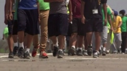 FILE - Unaccompanied immigrant children walk across a parking lot in a frame grab from video shot during a tour by White House officials and members of Congress, in Carrizo Springs, Texas, March 24, 2021.