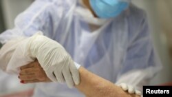 Una enfermera atiende a un paciente de edad avanzada contagiado con COVID-19 en Madrid, España.