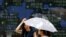 FILE - Women stand in front of a board showing market indices in Tokyo July 28, 2015.