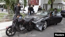 FILE - Policemen examine a damaged Ferrari at the home of the late Red Bull founder Chaleo Yoovidhaya in Bangkok, Sept. 3, 2012.The grandson of the owner of Red Bull — the famous energy drink from Thailand — has been linked to the hit-and-run death of a police officer.