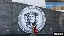 Un hombre camina frente al emblema de The City College of New York en Manhattan. 