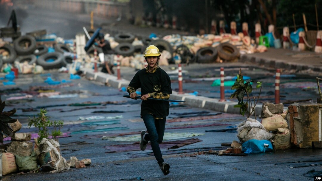 Seorang pengunjuk rasa berlari di sepanjang jalan sambil membawa pedang saat berlangsungnya penumpasan terhadap aksi protes menentang kudeta militer di Yangon, 16 Maret 2021. (Foto: STR / AFP)