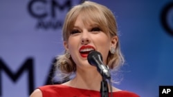 Taylor Swift poses backstage with her awards for musical event of the year and music video of the year for "Highway Don't Care," and pinnacle award at the 47th annual CMA Awards at Bridgestone Arena, Nov. 6, 2013, in Nashville, Tenn.