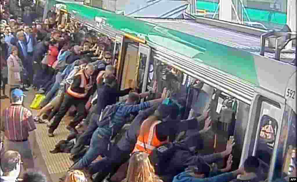 A frame grab from a video from the Public Transport Authority of Western Australia shows commuters pushing a train to free a passenger&#39;s leg trapped between the train and the gap in Perth.